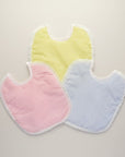 Three baby bibs in pastel colors on a light background