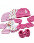 Collection of pink baby accessories including hats, mittens, and booties on a white background