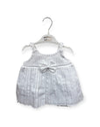 Baby dress with a bow on a hanger against a white background