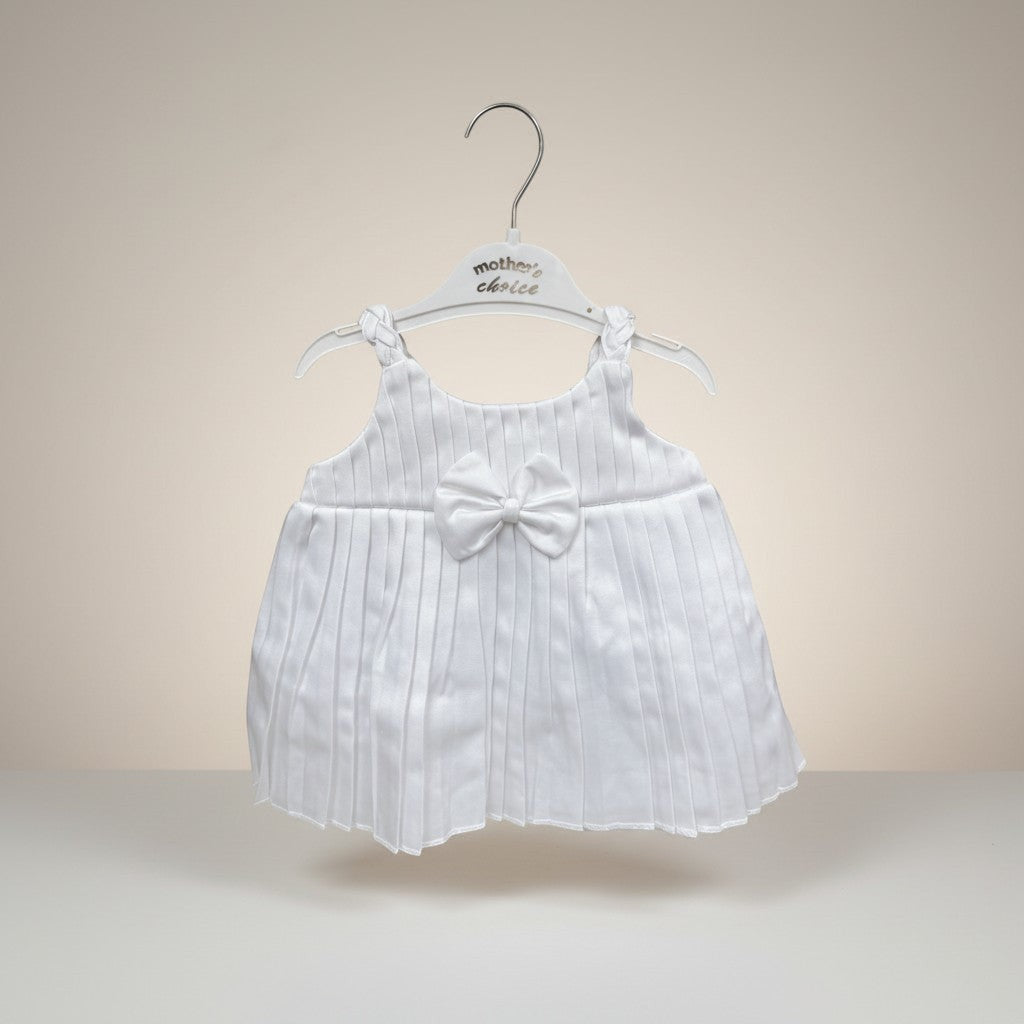 White baby dress with a bow on a hanger against a beige background