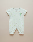 White baby romper with floral patterns on a beige background