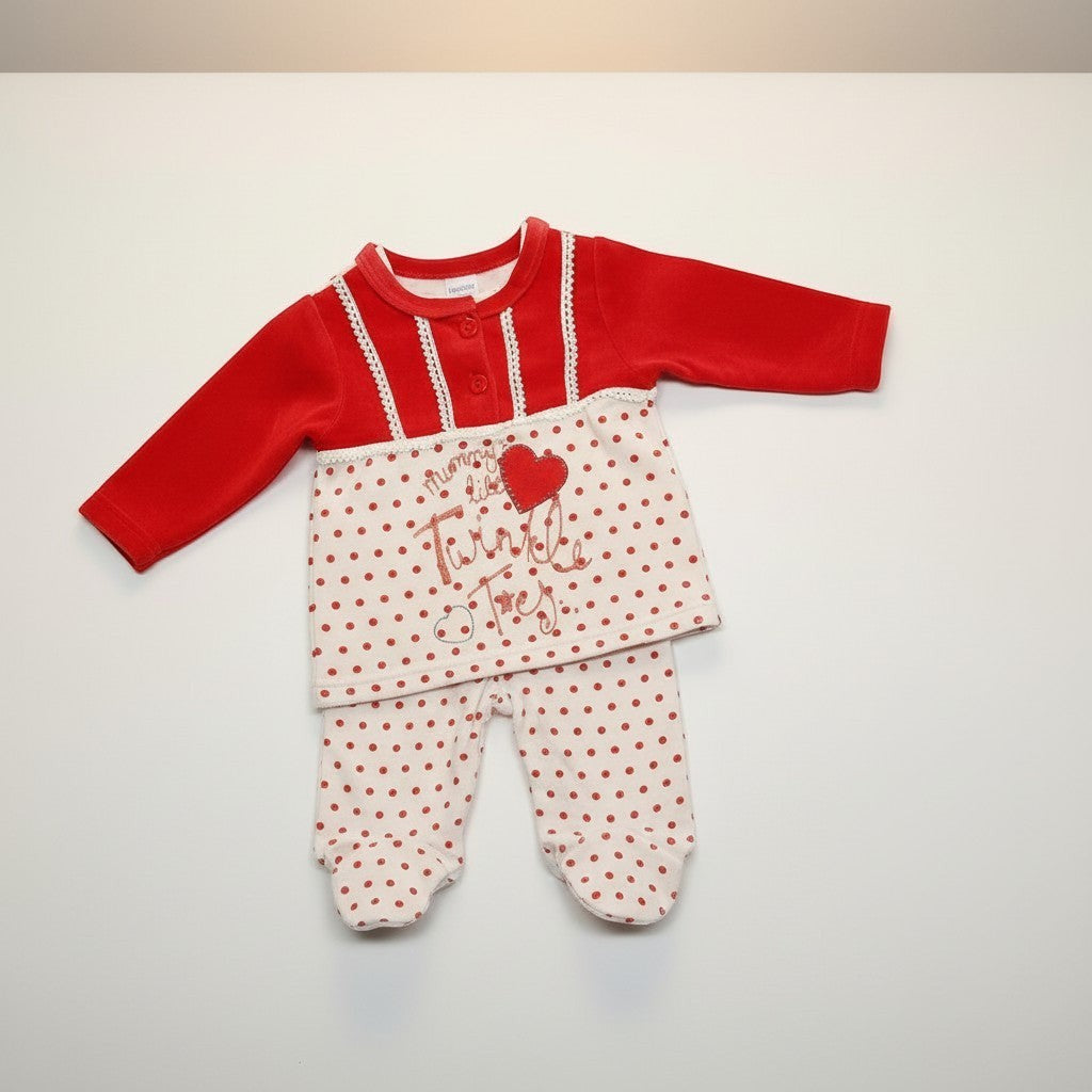 Baby outfit with red top and white pants with red polka dots on a light gray background