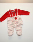 Baby outfit with red top and white pants with red polka dots on a light gray background