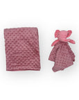 Pink textured blanket and plush elephant toy on a white background