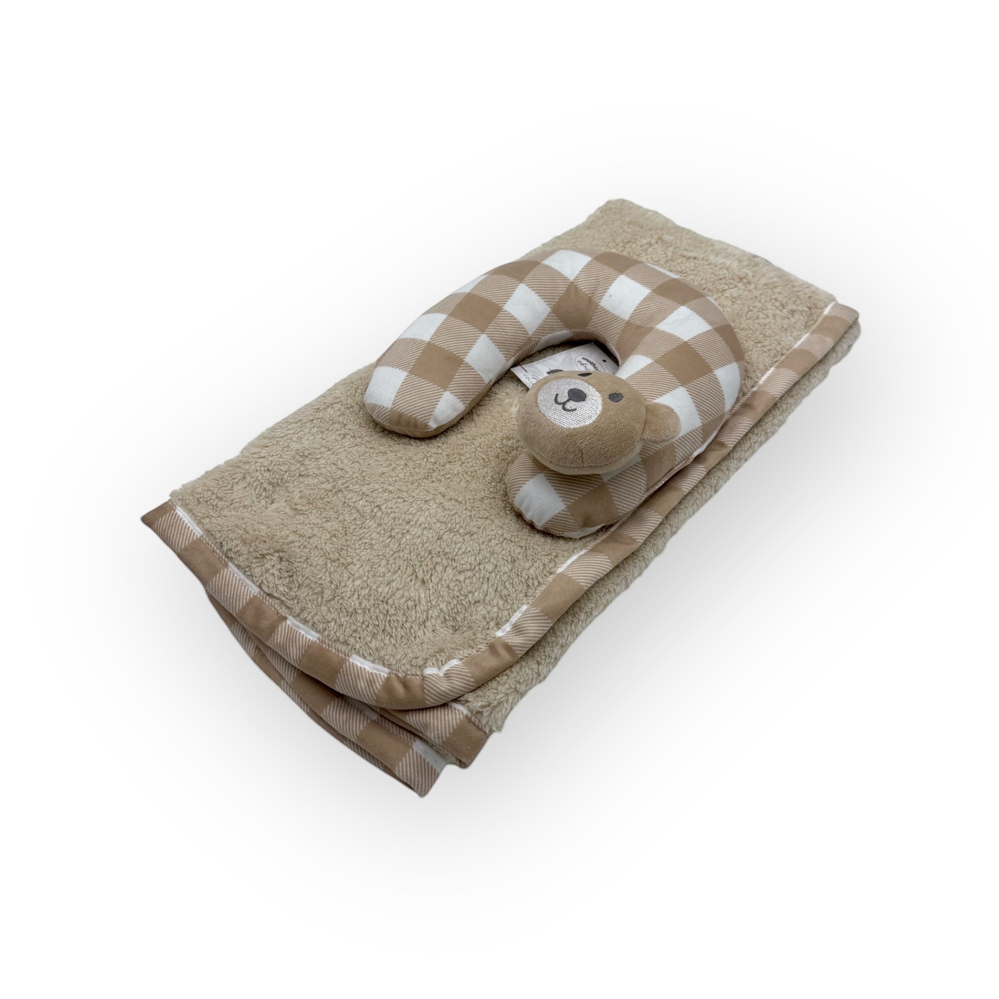 Baby pillow with checkered design and teddy bear toy on a beige towel