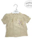 Beige baby blouse with floral design on a hanger against a white background