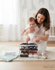 Stork and Baby 4-pack baby socks in PVC gift box, featuring brown, black, and red pairs with animal and stripe designs.
