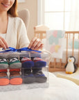 Stork And Baby 4 pack baby socks gift set with soccer, basketball, and striped designs in a clear box tied with a blue ribbon.