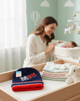 Stork And Baby navy blue knit beanie with red and white trim and "M311" graphic.