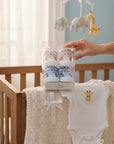 Stork And Baby Mothers Choice boys 2 pack socks gift set with blue and tan striped patterns, presented in a clear box next to a white giraffe bodysuit.