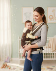 Stork And Baby brown 4-way baby carrier with adjustable straps, worn by a smiling mother holding a happy baby.