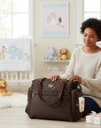 Stork And Baby brown diaper bag with multiple compartments and maroon straps, shown with a woman organizing it in a nursery.