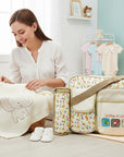 Stork And Baby beige diaper bag with 'little friends' embroidery, featuring a mother and baby setting.