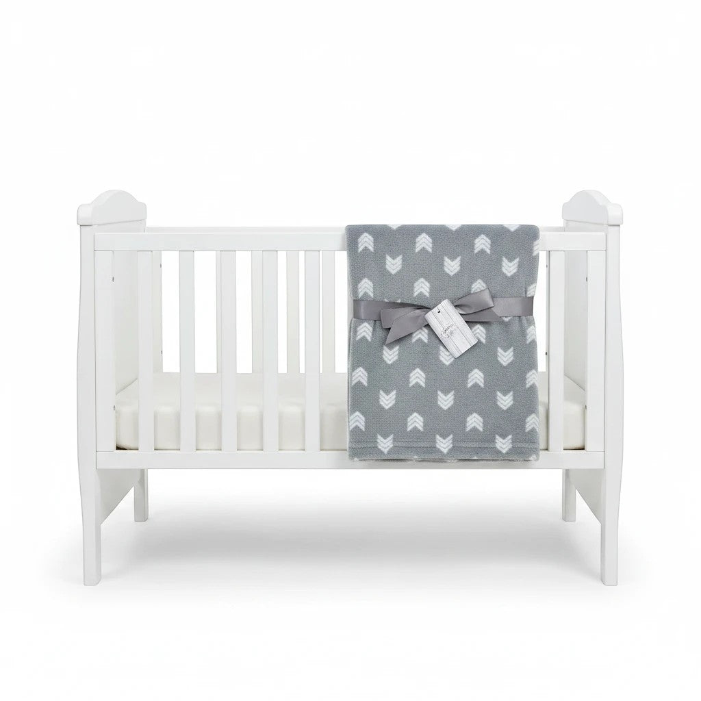Stork And Baby Mother's Choice grey fleece baby receiver blanket with white chevron pattern draped on a white crib.