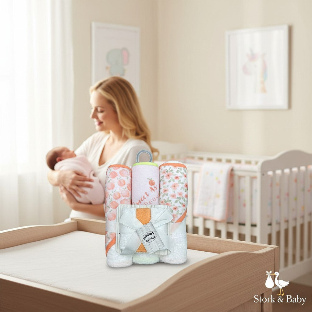 Stork And Baby 6-piece baby hooded towel and facecloth set with peach and floral prints. Soft, absorbent cotton for baby care.