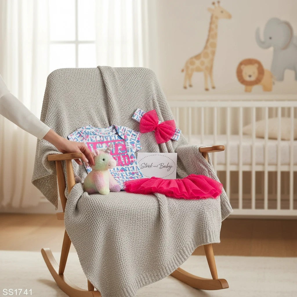 Stork and Baby pink and blue "Love" 3-piece infant set with unicorn plush, tutu, and headband on a chair.