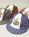 Stork And Baby infant boys check caps in plaid with cartoon ducks and chickens. Available in red, blue, and brown.