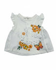 Stork And Baby white cotton infant girls 2-piece set with 'Be Kind' text, floral print, and butterfly detail. Ruffled sleeves and eyelet trim.