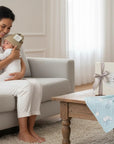 Stork And Baby mother holding a baby wearing a tan jacquard knit winter hat with a tag.
