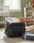 Stork And Baby dark grey medium diaper bag with organized baby essentials inside, including clothes and a giraffe toy.