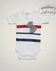 Stork And Baby white cotton romper for girls with red, navy, and striped bow detail. Nautical style.