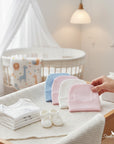 Stork And Baby pastel baby beanies in pink, white, and blue, made of 100% cotton.