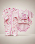 Stork And Baby pink deer 5-piece newborn starter pack with babygrow, onesie, bib, and mittens. Soft cotton fabric.