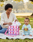 Stork And Baby insulated bottle warmer bag in pink geo pattern, with a woman and baby on a picnic blanket.
