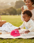 Stork And Baby pink cotton cap with embroidered hearts and "Hugs and Kisses" for girls.