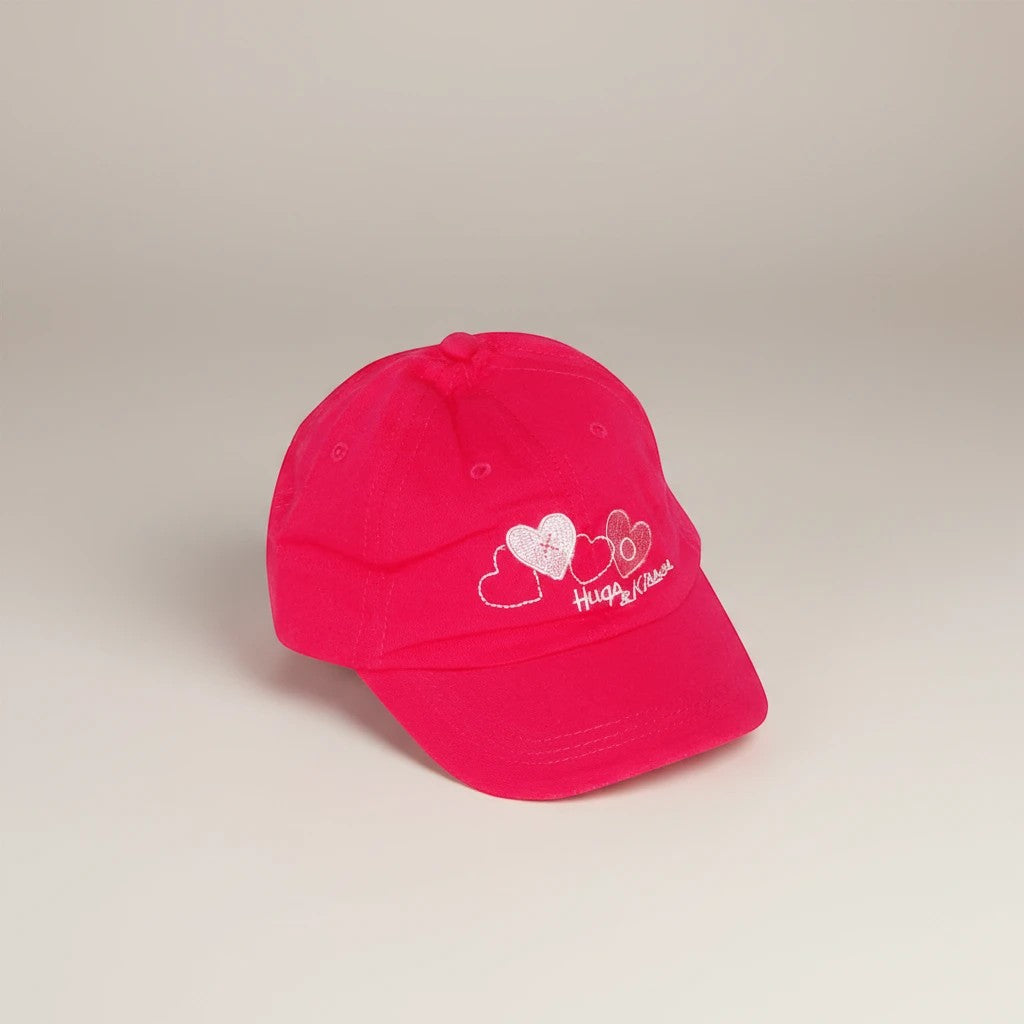 Stork And Baby pink cotton cap with embroidered hearts and "Hugs &amp; Kisses" text for girls.