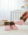 Stork And Baby pink polka dot baby socks with brown fuzzy cuffs, presented in a gift box.