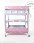 Stork And Baby pink baby bath caddy with white star pattern, storage compartments, and drainage tube on wheels