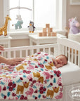 Stork And Baby white polyester receiver blanket with deer, flowers, and trees in pink, gold, and teal.