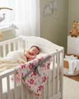 Stork And Baby white 100% polyester receiver blanket with pink floral pattern, grey ribbon, and a sleeping baby.