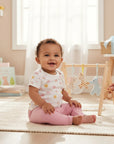 Stork And Baby 8 piece gift set with rainbow, sun, and cloud print bodysuit and pink bottoms for a baby.