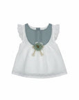 Stork And Baby white cotton linen dress with blue yoke, ruffled sleeves, and floral embellishment.