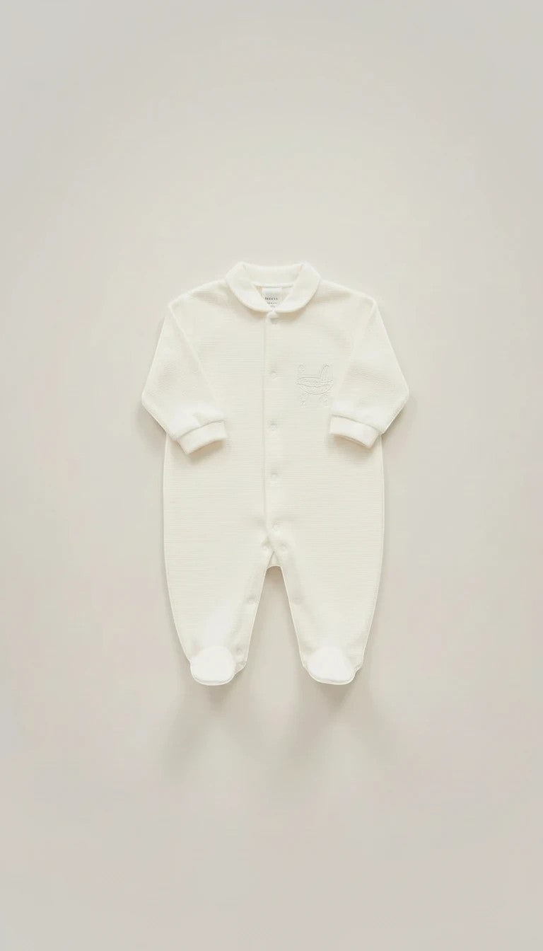 Stork And Baby white footed romper with silver embroidery detail on chest. Long sleeves, collared neckline, and button front.