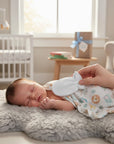 Stork And Baby white fleece infant mittens on a sleeping baby, soft and cozy for chilly weather.
