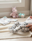 Stork And Baby white 100% cotton baby leggings with a black grid pattern. Footed design for comfort.
