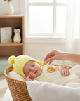 Stork And Baby yellow knitted trapper beanie with pompom on sleeping baby